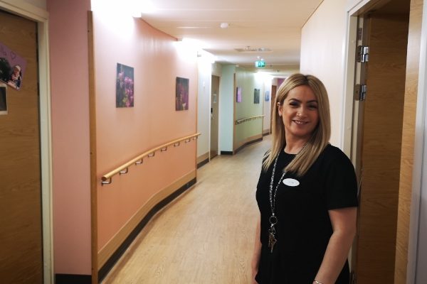 Hoitaja hymyilee palvelukodin käytävällä Hoitaja hymyilee palvelukodin käytävällä